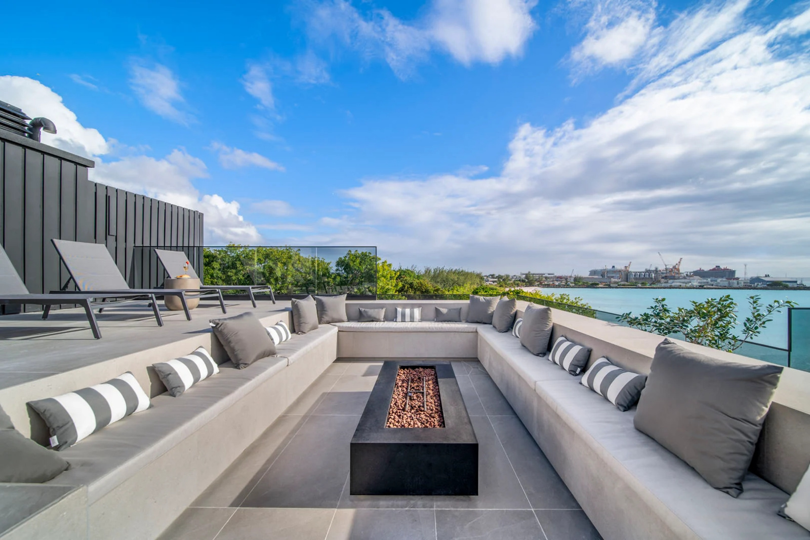 Chic rooftop lounge with cozy cushions and firepit, offering sweeping coastal views in Barbados
