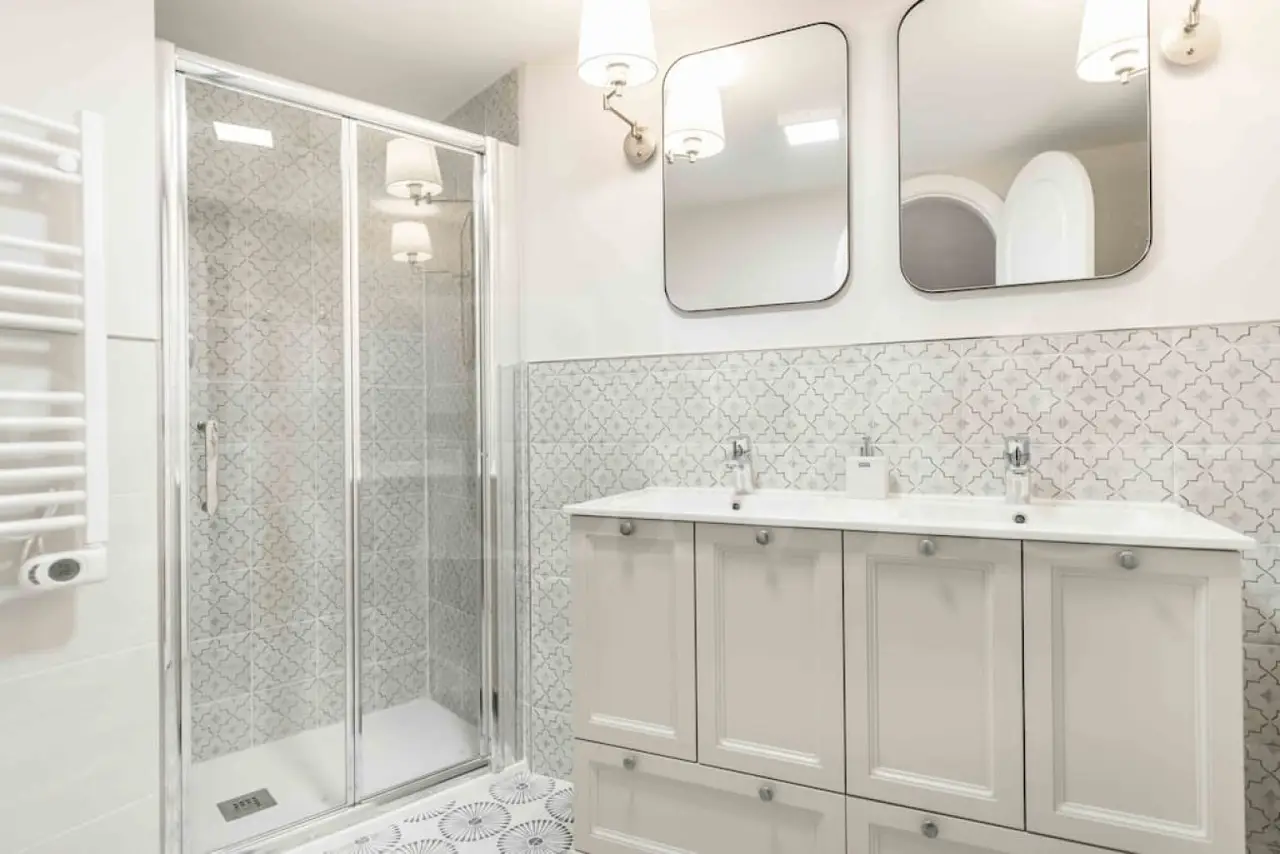 Elegant bathroom with patterned Spanish tiles, walk-in glass shower, and contemporary sink—highlighting the boutique comfort of the Malaga stay included in Charity Ace's Spain experience for 4.