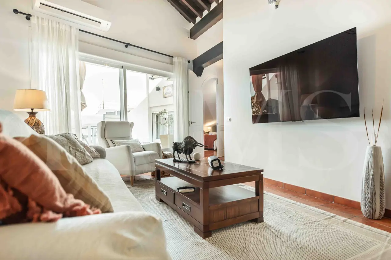 Stylish Andalusian-inspired living room with natural light, terracotta floors, and cozy neutral-toned furnishings in a luxury apartment for 4 guests in Malaga, Spain.