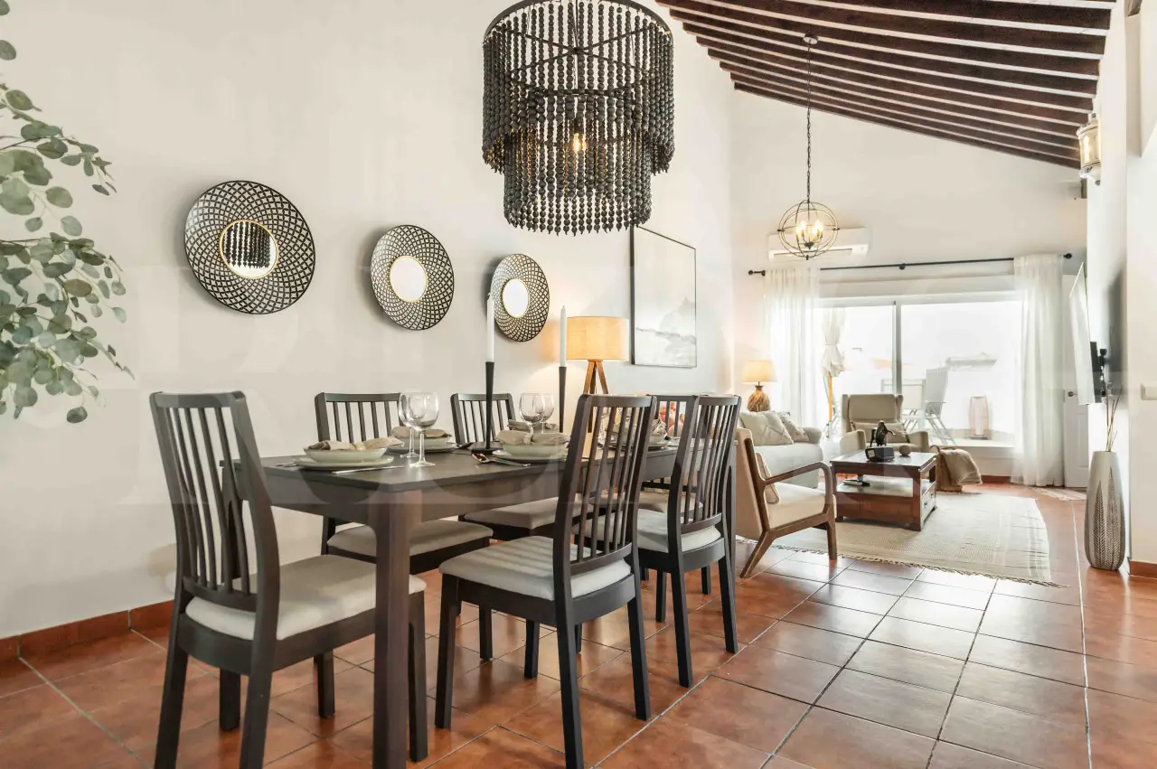 Elegant dining area with vaulted wooden ceilings and open-concept kitchen in a spacious Malaga apartment included in Charity Ace’s Spain auction package.