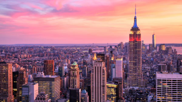 New York City Skyline at Sunset – A breathtaking aerial view of New York City at sunset, featuring the Empire State Building illuminated against a vibrant pink and orange sky. A perfect auction package destination for an unforgettable urban getaway.