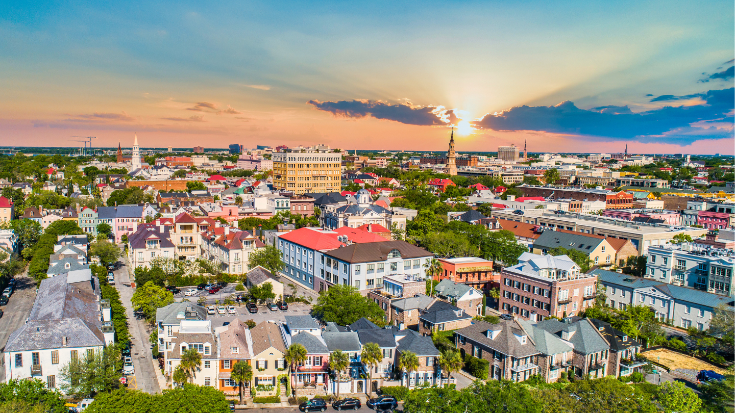 Charleston Historic District at Sunset – A charming aerial view of Charleston, South Carolina, showcasing colorful historic homes, cobblestone streets, and a picturesque sunset. A must-have CharityACE auction experience for a Southern retreat.