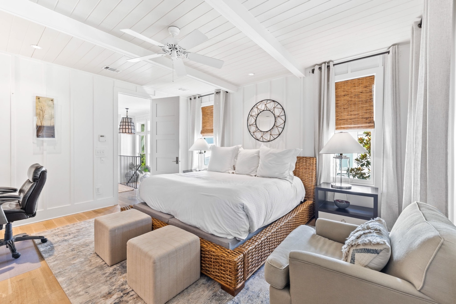 Spacious primary bedroom with wicker bed frame, soft lighting, and elegant coastal decor in Watercolor, Florida