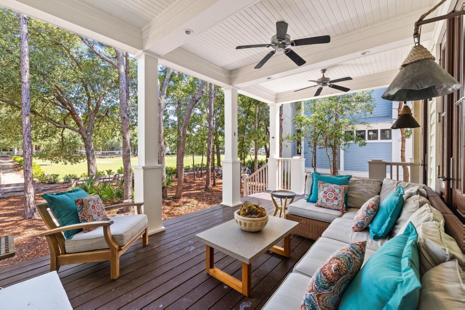 Spacious porch with ceiling fans, plush seating, and nature views in a tranquil Watercolor, Florida vacation home
