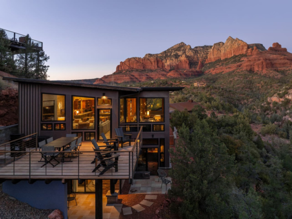 Sedona luxury rental at twilight with glowing interior and striking red rock mountain backdrop.